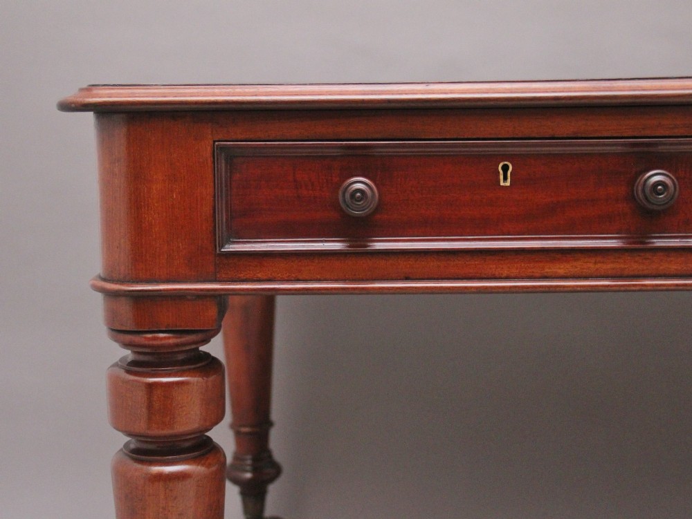 A 19th-century mahogany partners writing table featuring three drawers with turned wooden knobs, an inset leather surface, and four turned legs on brass castors. View III