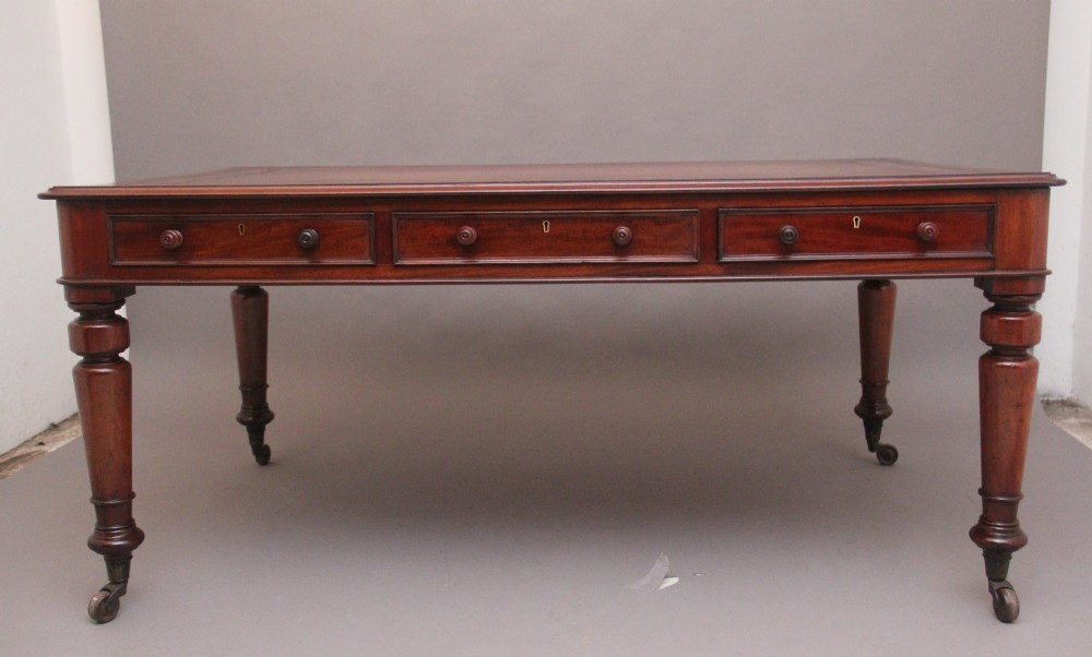 A 19th-century mahogany partners writing table featuring three drawers with turned wooden knobs, an inset leather surface, and four turned legs on brass castors. View VI