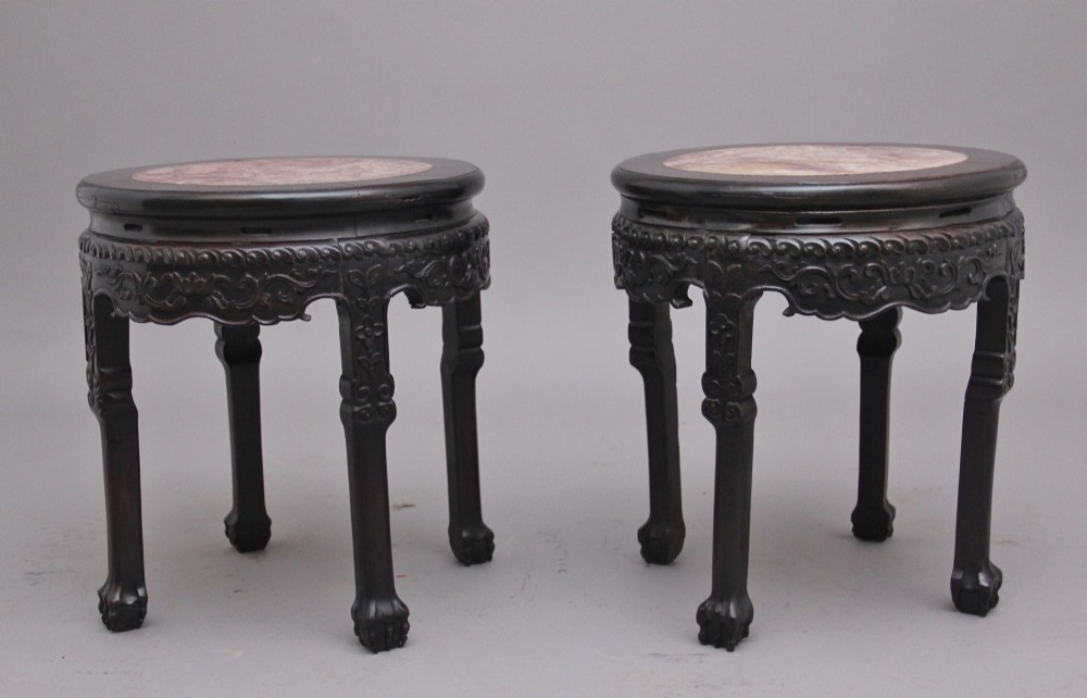 A pair of 19th-century Chinese carved dark hardwood circular occasional tables with inset pink marble tops and carved legs. View X