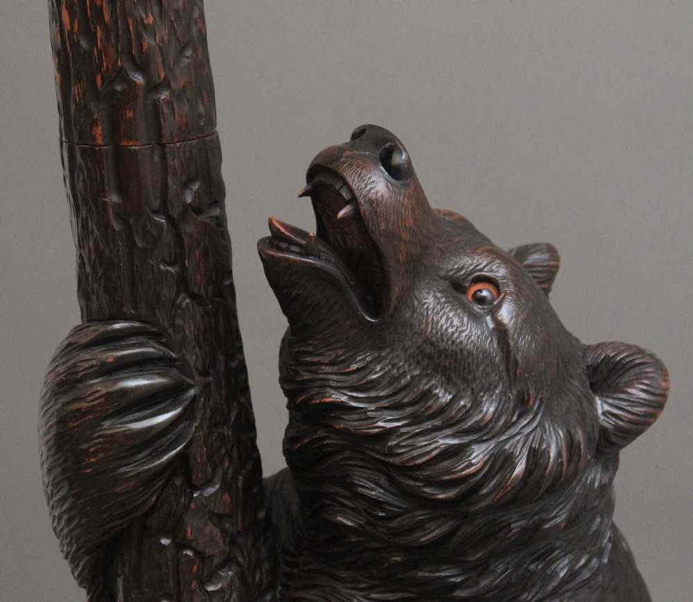 A 19th-century hand-carved Black Forest hall stand featuring two carved bear figures, branch-form coat hooks, small mirrors, and an umbrella ring base. View VI