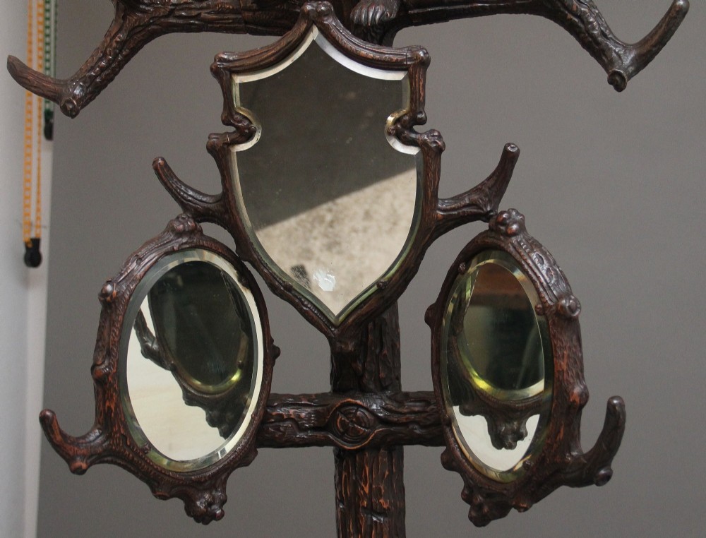 A 19th-century hand-carved Black Forest hall stand featuring two carved bear figures, branch-form coat hooks, small mirrors, and an umbrella ring base. View VIII