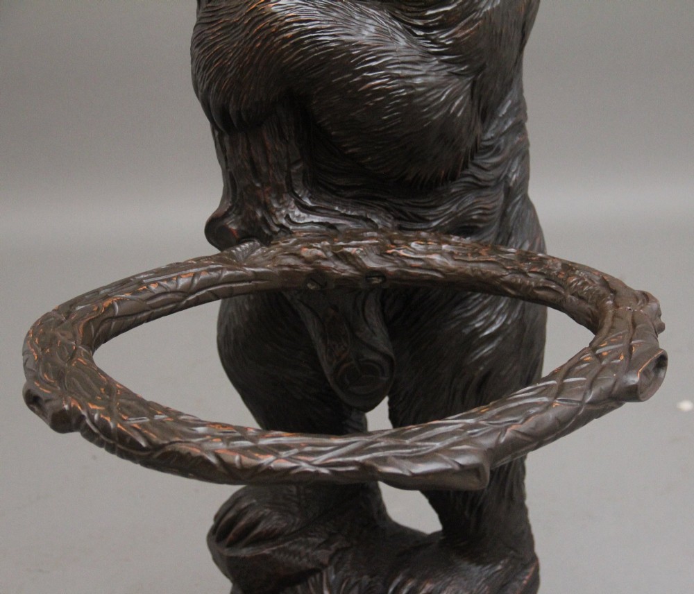 A 19th-century hand-carved Black Forest hall stand featuring two carved bear figures, branch-form coat hooks, small mirrors, and an umbrella ring base. View IX