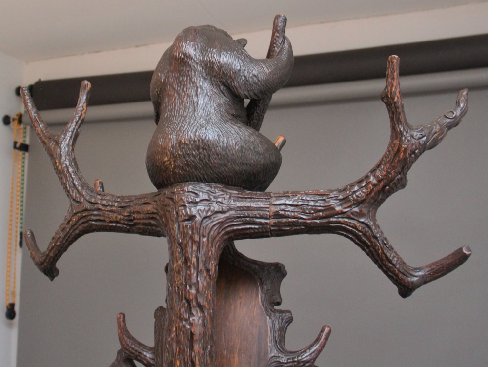 A 19th-century hand-carved Black Forest hall stand featuring two carved bear figures, branch-form coat hooks, small mirrors, and an umbrella ring base. View X