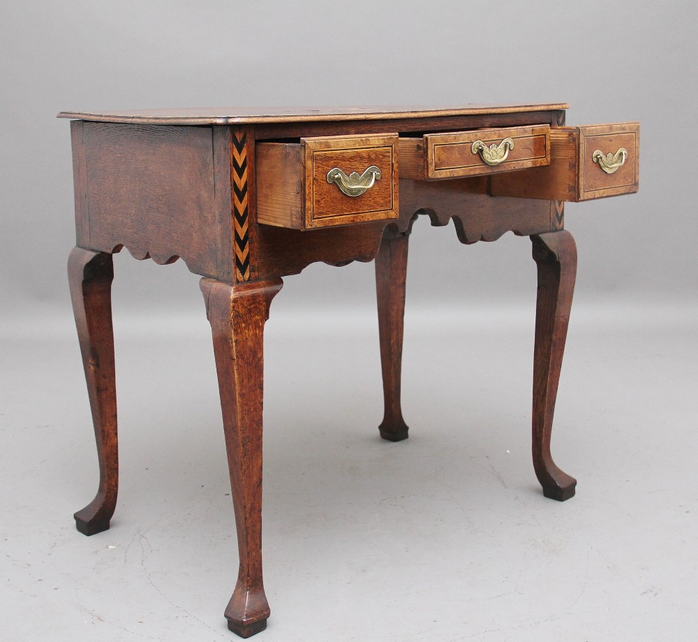 An 18th-century oak lowboy table featuring three drawers with brass handles, inlaid chevron borders, a scalloped apron, and four cabriole legs. View III