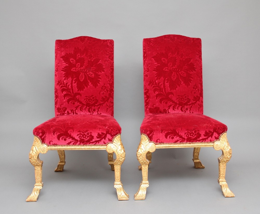 A pair of George I style giltwood side chairs featuring carved mask motifs on the legs and upholstered in rich red patterned velvet. View II