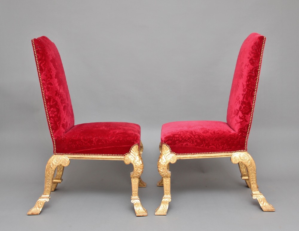 A pair of George I style giltwood side chairs featuring carved mask motifs on the legs and upholstered in rich red patterned velvet. View III