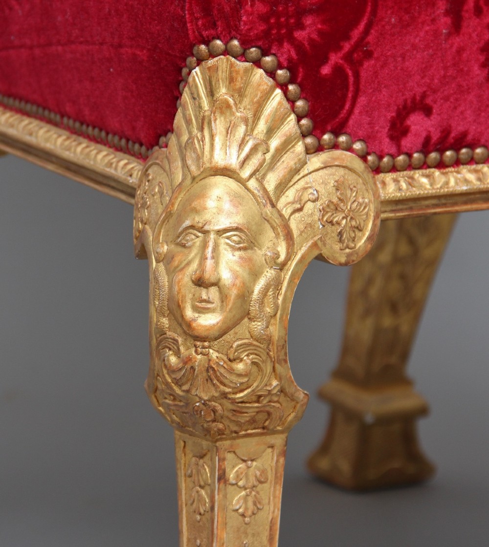 A pair of George I style giltwood side chairs featuring carved mask motifs on the legs and upholstered in rich red patterned velvet. View VI