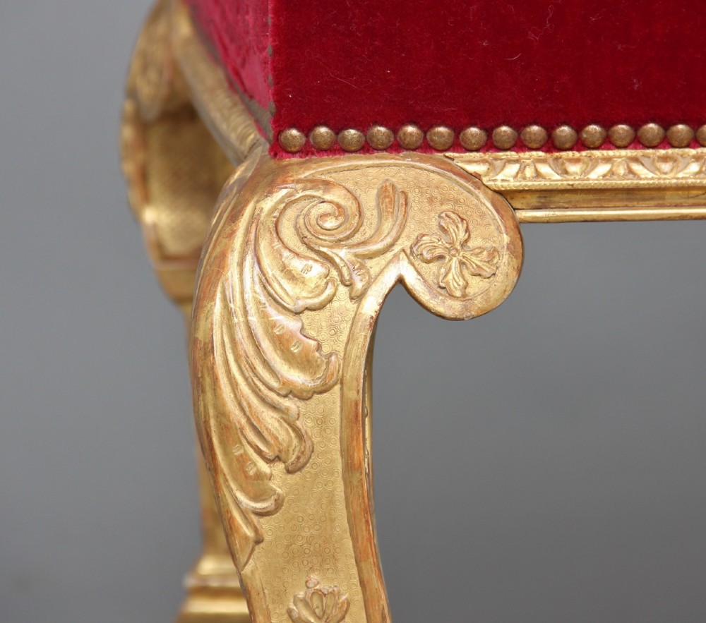 A pair of George I style giltwood side chairs featuring carved mask motifs on the legs and upholstered in rich red patterned velvet. View X