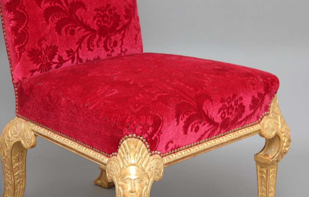 A pair of George I style giltwood side chairs featuring carved mask motifs on the legs and upholstered in rich red patterned velvet. View XIII