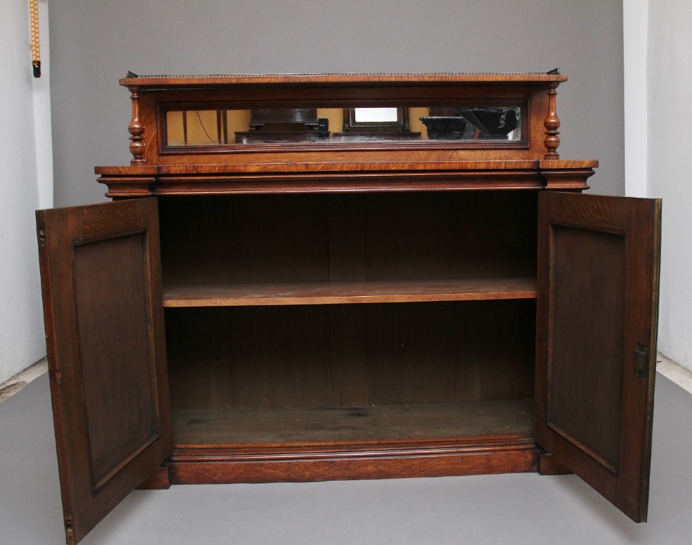A nineteenth-century pollard oak cabinet featuring a mirrored gallery top, fluted column pillars, and twin doors with fabric-lined panels. View II