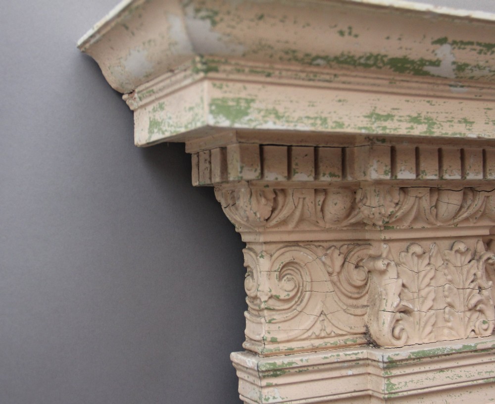 An 18th-century carved pine architectural overmantel featuring a broken pediment, fluted pilasters, dentil mouldings, and a central circular aperture in distressed off-white paint. View XI