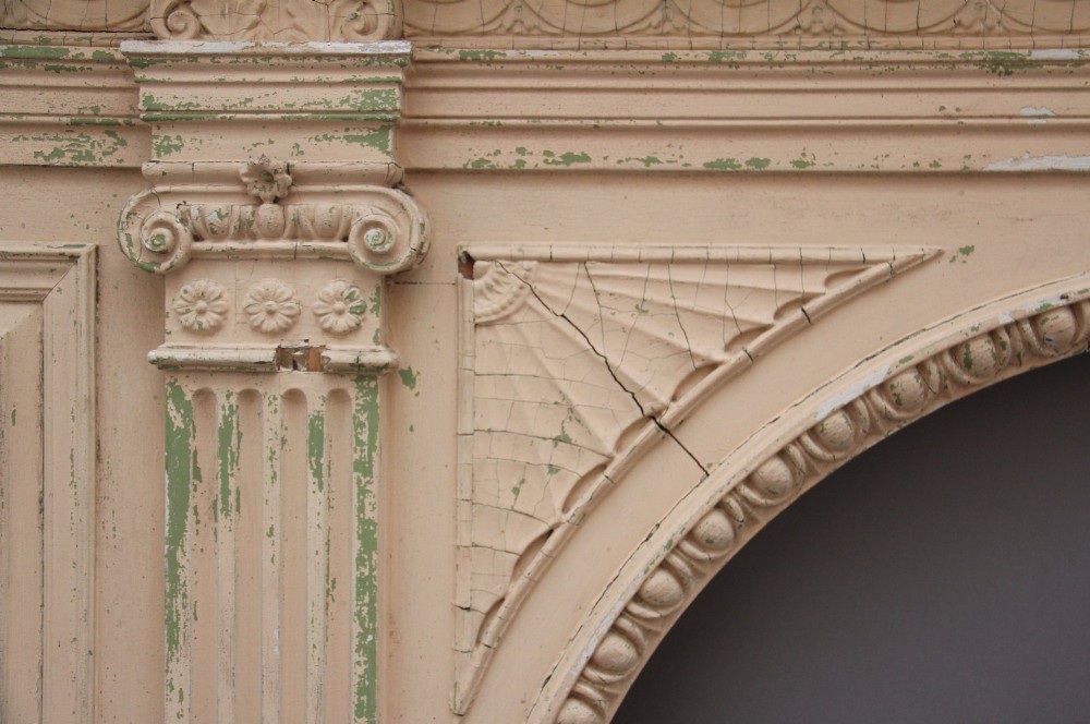 An 18th-century carved pine architectural overmantel featuring a broken pediment, fluted pilasters, dentil mouldings, and a central circular aperture in distressed off-white paint. View XII