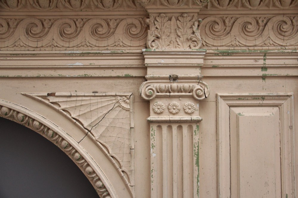 An 18th-century carved pine architectural overmantel featuring a broken pediment, fluted pilasters, dentil mouldings, and a central circular aperture in distressed off-white paint. View XIII