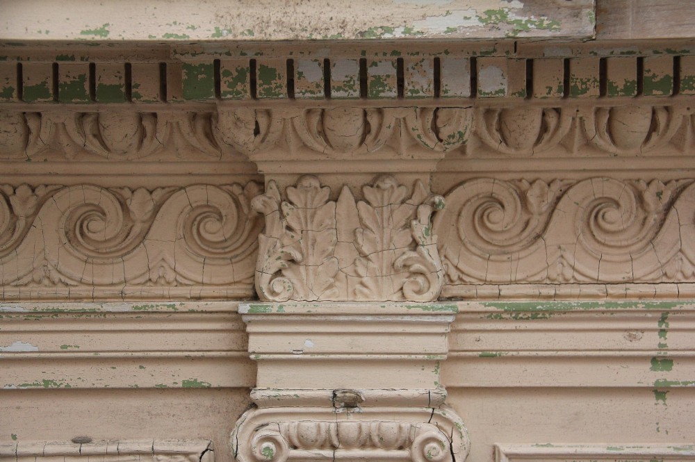 An 18th-century carved pine architectural overmantel featuring a broken pediment, fluted pilasters, dentil mouldings, and a central circular aperture in distressed off-white paint. View XIV