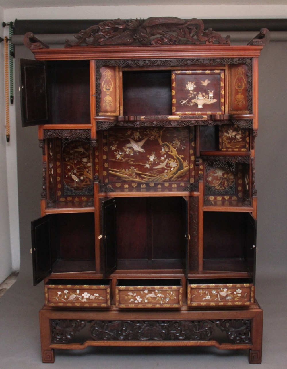 A large 19th-century Japanese hardwood Shodona cabinet featuring asymmetric shelves, carved dragon cresting, and panel doors adorned with lacquer and mother-of-pearl bird motifs. View II