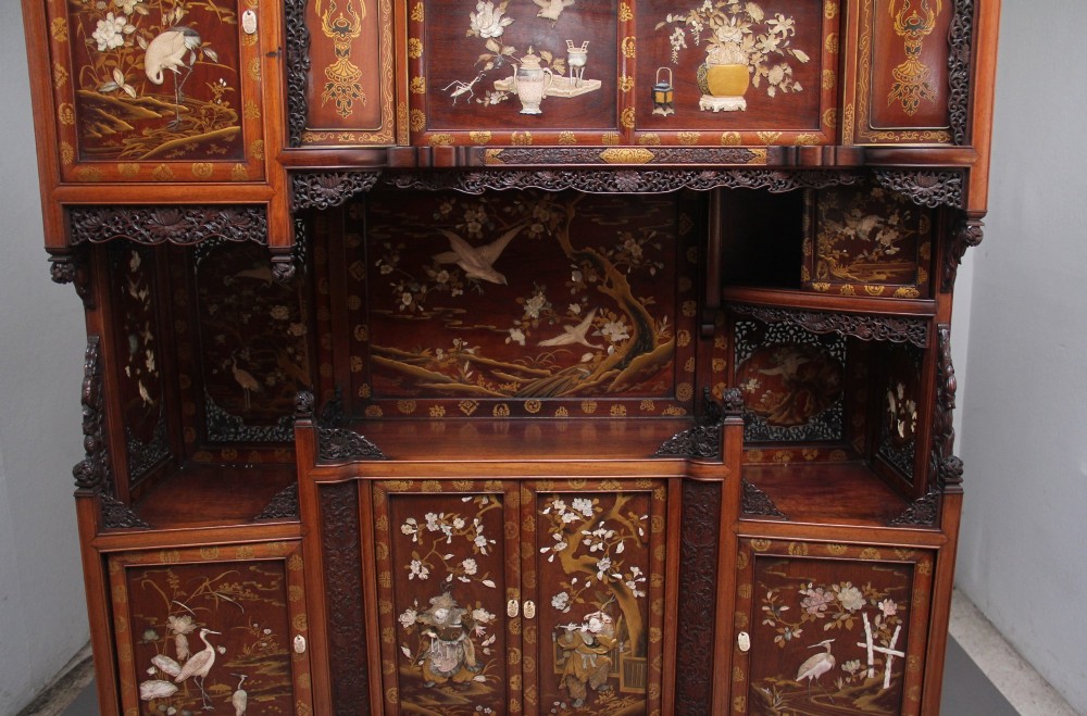 A large 19th-century Japanese hardwood Shodona cabinet featuring asymmetric shelves, carved dragon cresting, and panel doors adorned with lacquer and mother-of-pearl bird motifs. View X