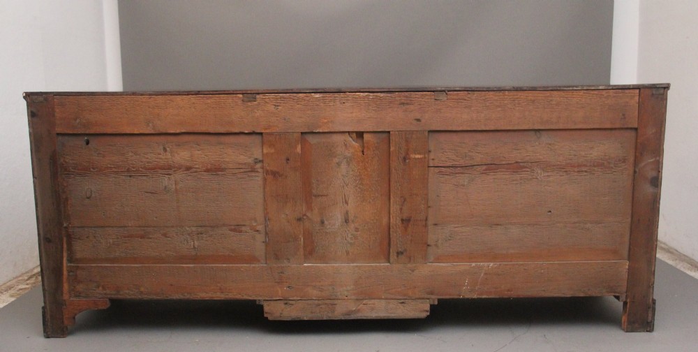 A large 18th-century oak dresser base featuring brass swan-neck handles, multiple drawers, a central panelled cupboard, and bracket feet. View VIII