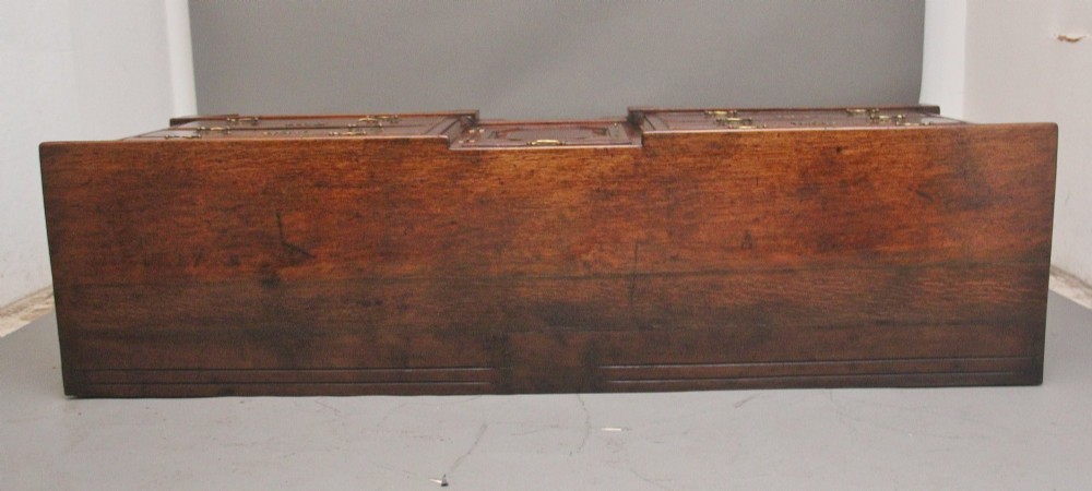 A large 18th-century oak dresser base featuring brass swan-neck handles, multiple drawers, a central panelled cupboard, and bracket feet. View X