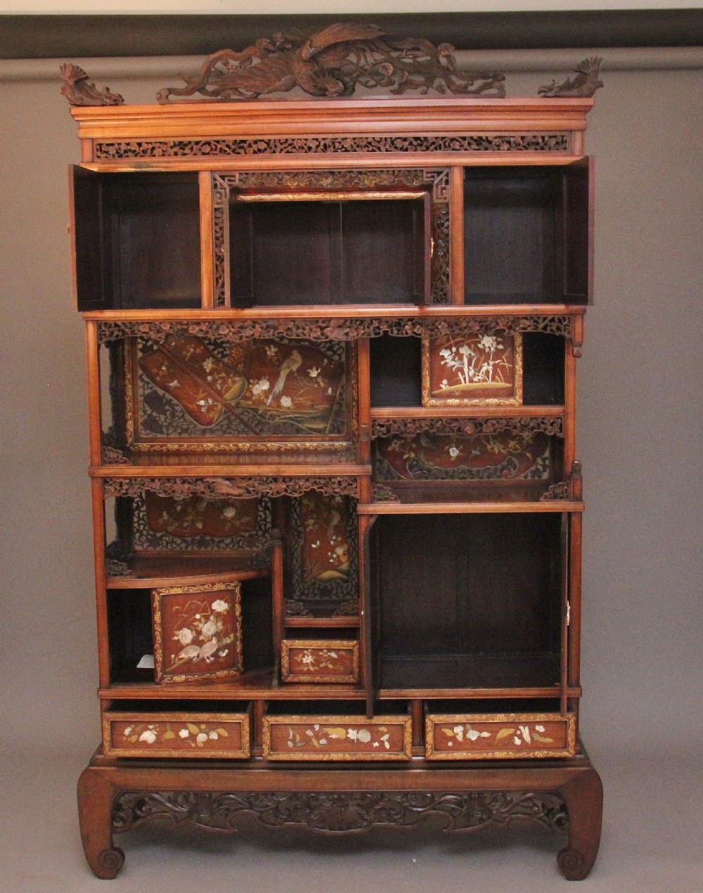 A 19th-century Japanese Meiji period shodona display cabinet with asymmetrical lacquered doors, bird and floral shibayama inlays, and carved cresting. View II