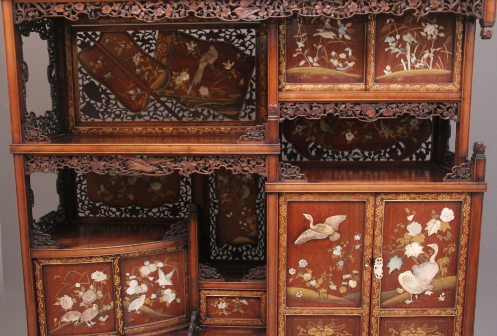 A 19th-century Japanese Meiji period shodona display cabinet with asymmetrical lacquered doors, bird and floral shibayama inlays, and carved cresting. View V