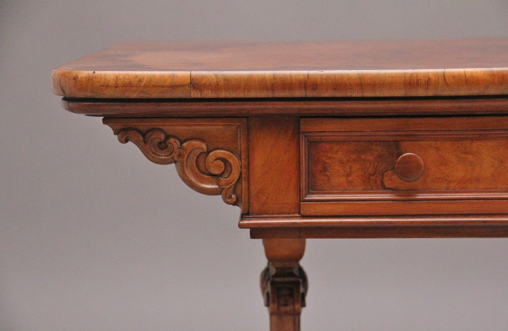 A 19th-century burr walnut library table with two frieze drawers, carved scroll brackets, dual pedestal legs, and a central turned stretcher. View II