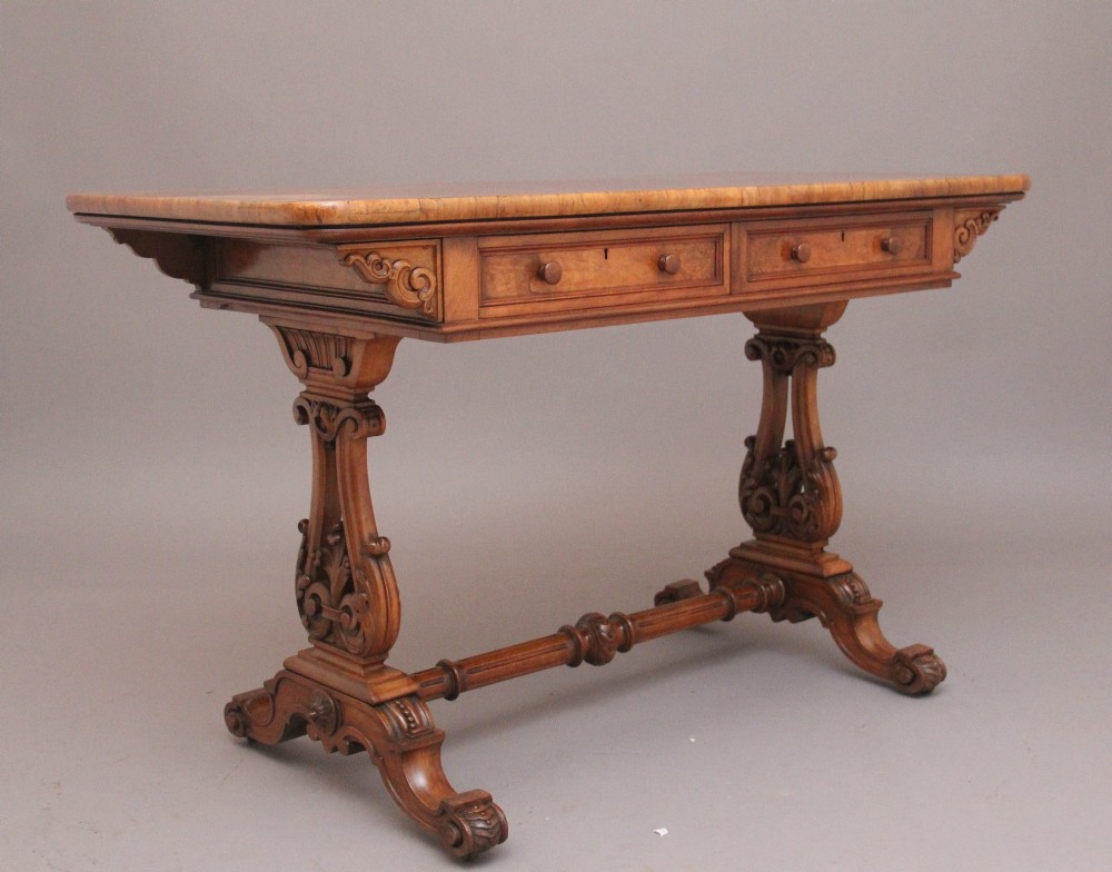 A 19th-century burr walnut library table with two frieze drawers, carved scroll brackets, dual pedestal legs, and a central turned stretcher. View V