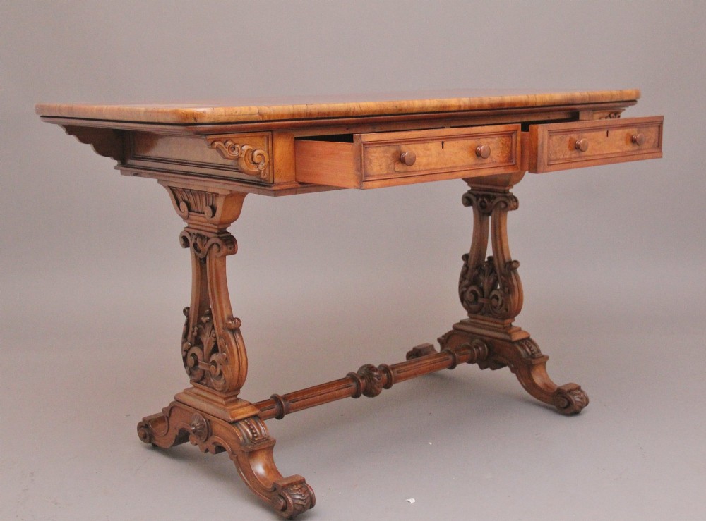 A 19th-century burr walnut library table with two frieze drawers, carved scroll brackets, dual pedestal legs, and a central turned stretcher. View VII