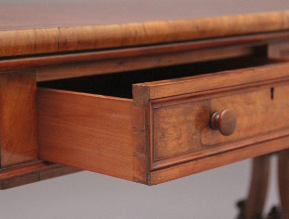 A 19th-century burr walnut library table with two frieze drawers, carved scroll brackets, dual pedestal legs, and a central turned stretcher. View IX