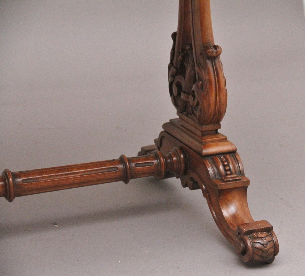 A 19th-century burr walnut library table with two frieze drawers, carved scroll brackets, dual pedestal legs, and a central turned stretcher. View X