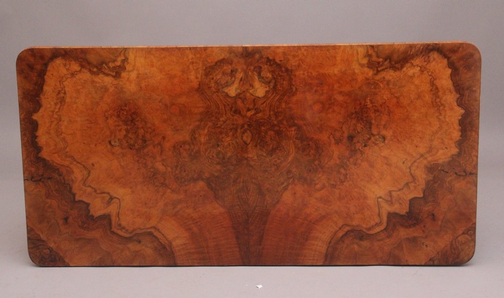 A 19th-century burr walnut library table with two frieze drawers, carved scroll brackets, dual pedestal legs, and a central turned stretcher. View XI