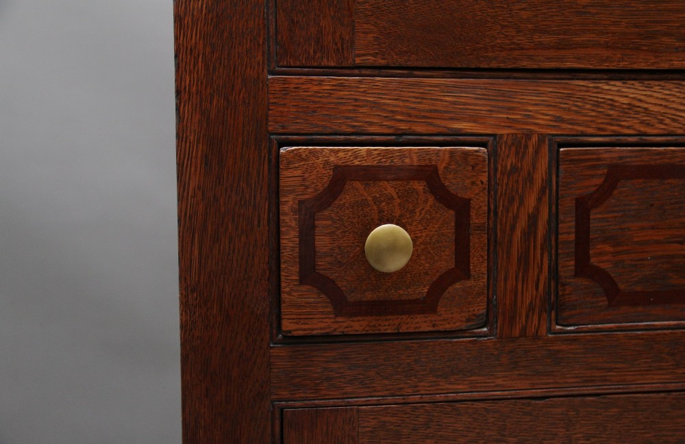 An early 19th-century dark oak food cupboard featuring pierced lattice ventilation panels, brass drawer handles, and panelled double doors. View X