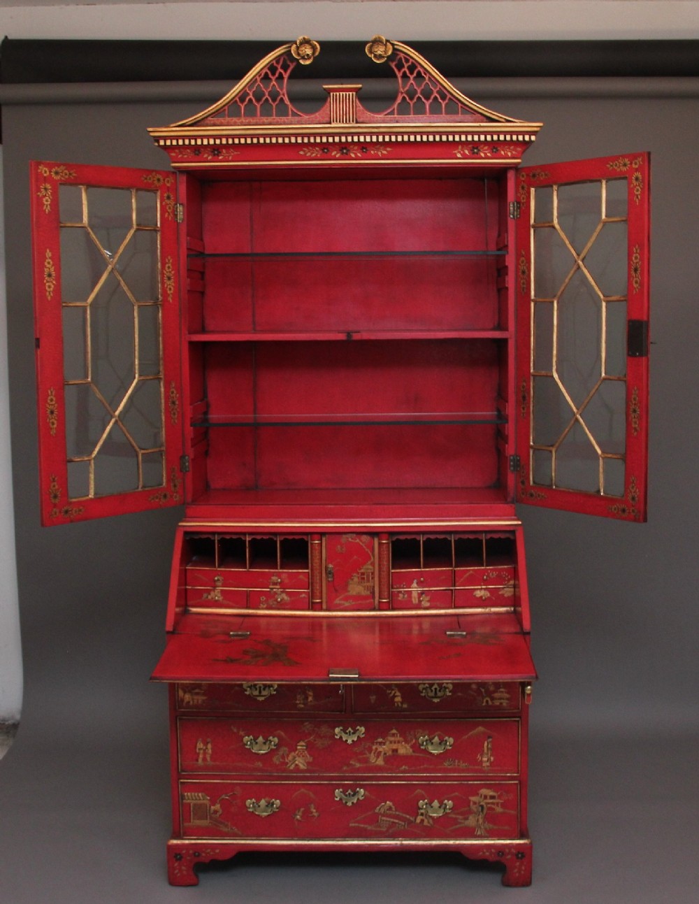 An early twentieth-century red lacquered Chinoiserie bureau bookcase decorated with gilded landscapes, double glazed doors, and brass drop handles. View III