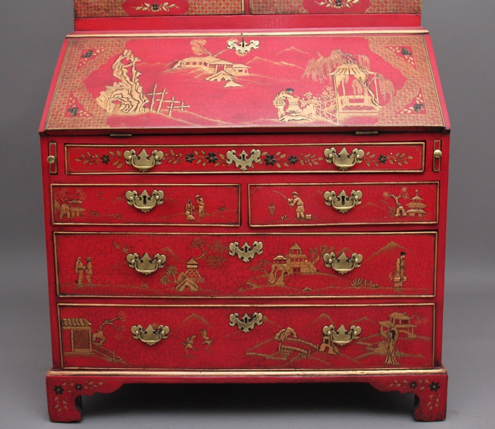 An early twentieth-century red lacquered Chinoiserie bureau bookcase decorated with gilded landscapes, double glazed doors, and brass drop handles. View IV
