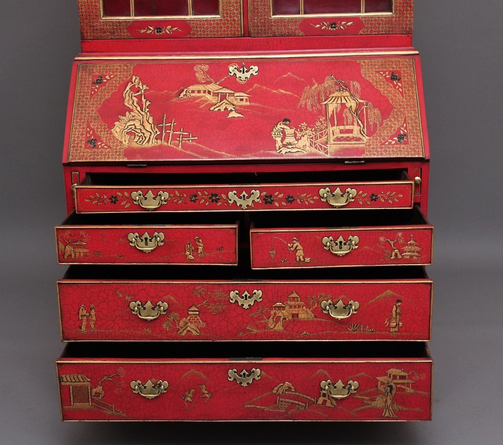 An early twentieth-century red lacquered Chinoiserie bureau bookcase decorated with gilded landscapes, double glazed doors, and brass drop handles. View V
