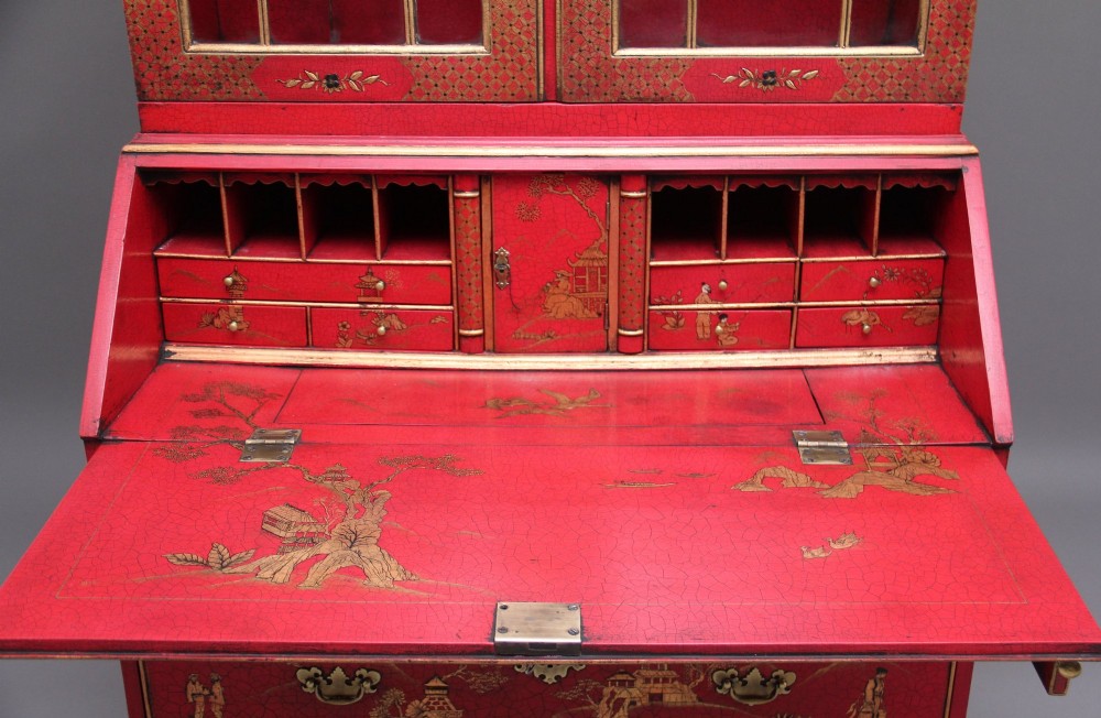 An early twentieth-century red lacquered Chinoiserie bureau bookcase decorated with gilded landscapes, double glazed doors, and brass drop handles. View IX