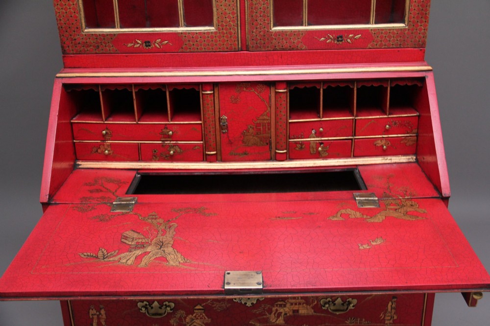 An early twentieth-century red lacquered Chinoiserie bureau bookcase decorated with gilded landscapes, double glazed doors, and brass drop handles. View X