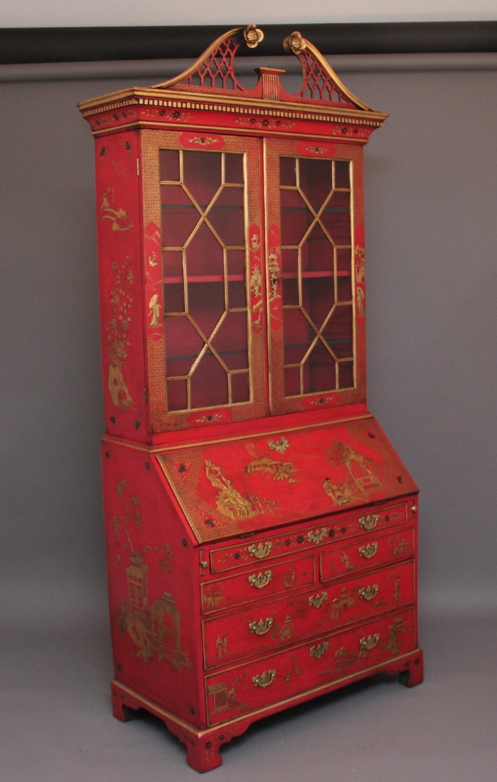 An early twentieth-century red lacquered Chinoiserie bureau bookcase decorated with gilded landscapes, double glazed doors, and brass drop handles. View XIII