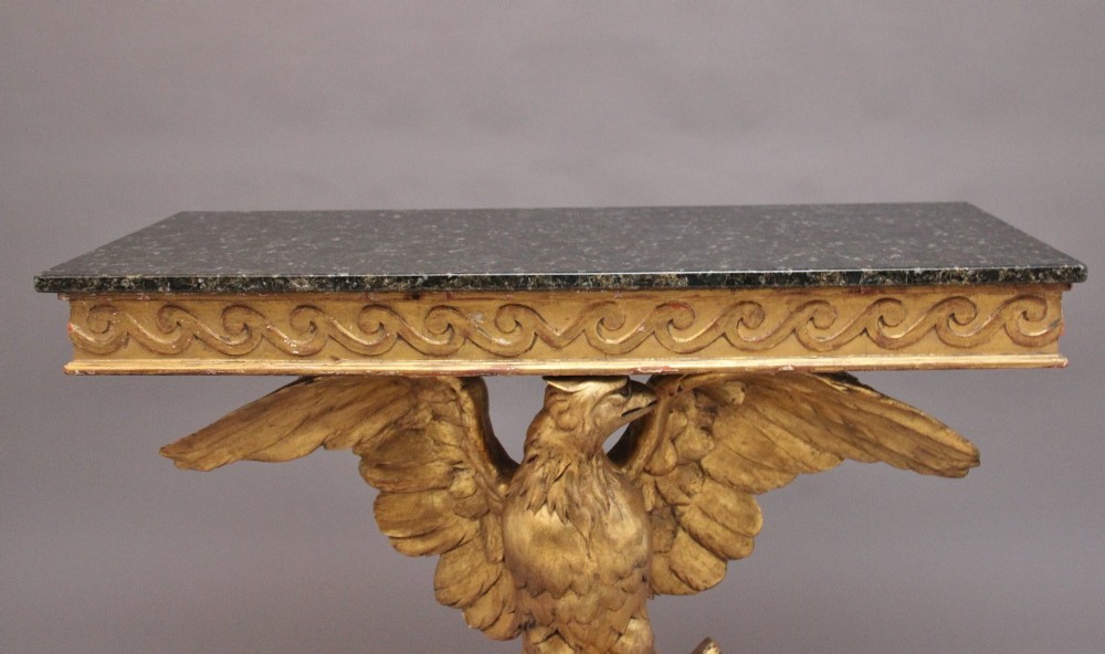 An early 20th-century console table featuring a dark marble top supported by a carved golden eagle pedestal on a matching marble base. View II