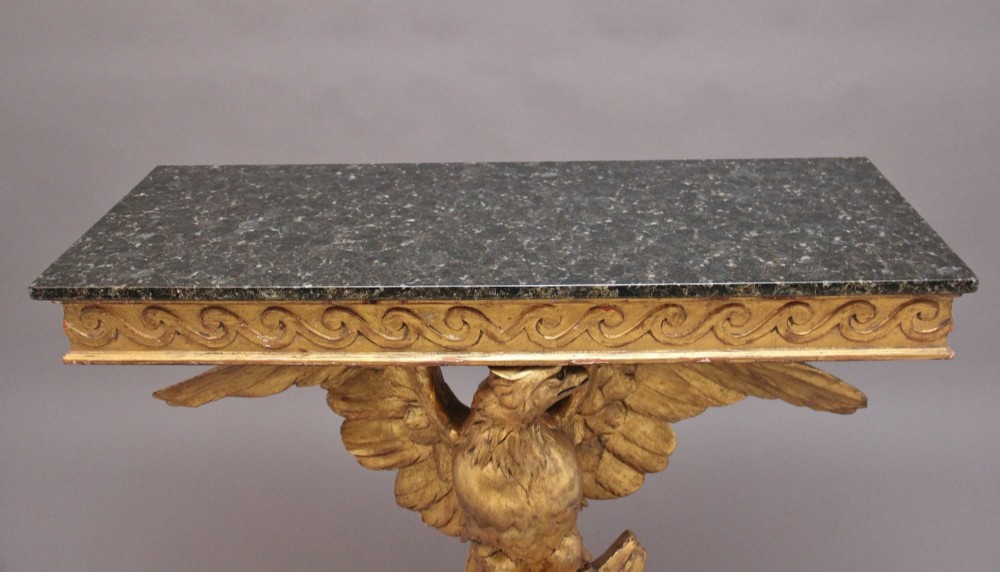 An early 20th-century console table featuring a dark marble top supported by a carved golden eagle pedestal on a matching marble base. View III