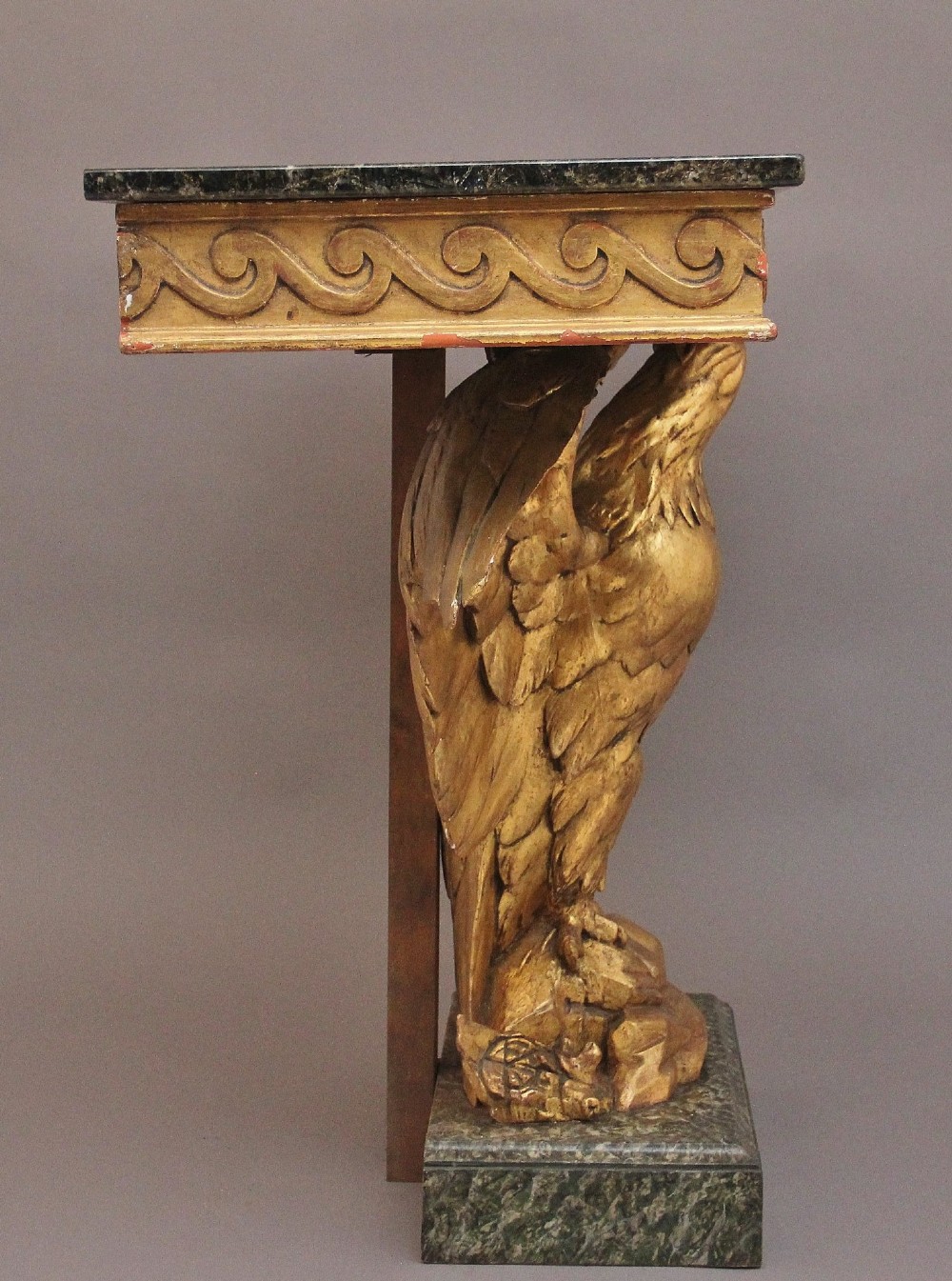 An early 20th-century console table featuring a dark marble top supported by a carved golden eagle pedestal on a matching marble base. View VI