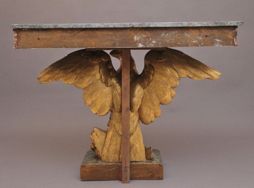 An early 20th-century console table featuring a dark marble top supported by a carved golden eagle pedestal on a matching marble base. View VII
