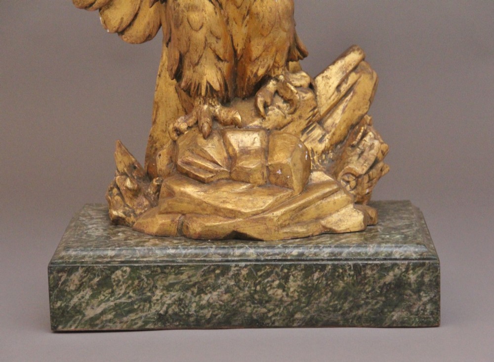 An early 20th-century console table featuring a dark marble top supported by a carved golden eagle pedestal on a matching marble base. View IX