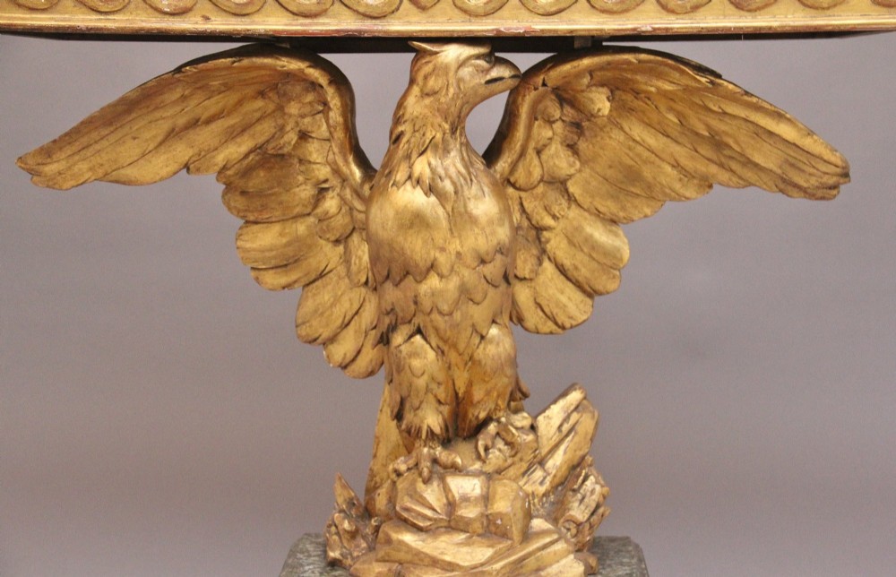 An early 20th-century console table featuring a dark marble top supported by a carved golden eagle pedestal on a matching marble base. View X