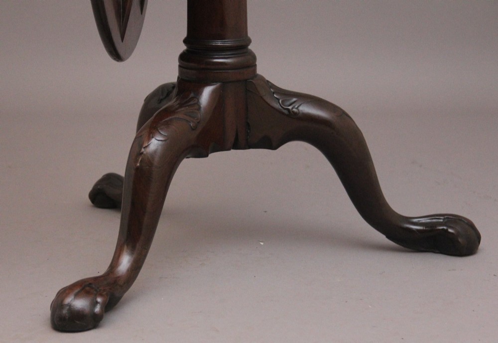 An 18th-century mahogany tripod table with its round top tilted upright on a turned column with three carved legs. View VII