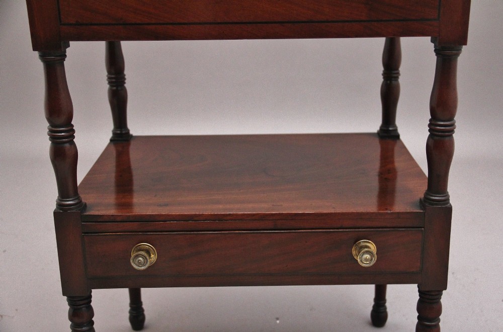 An early Victorian mahogany washstand featuring a gallery splashback top with circular aperture cutouts, a central open shelf, turned legs, and a bottom drawer with brass handles. View X