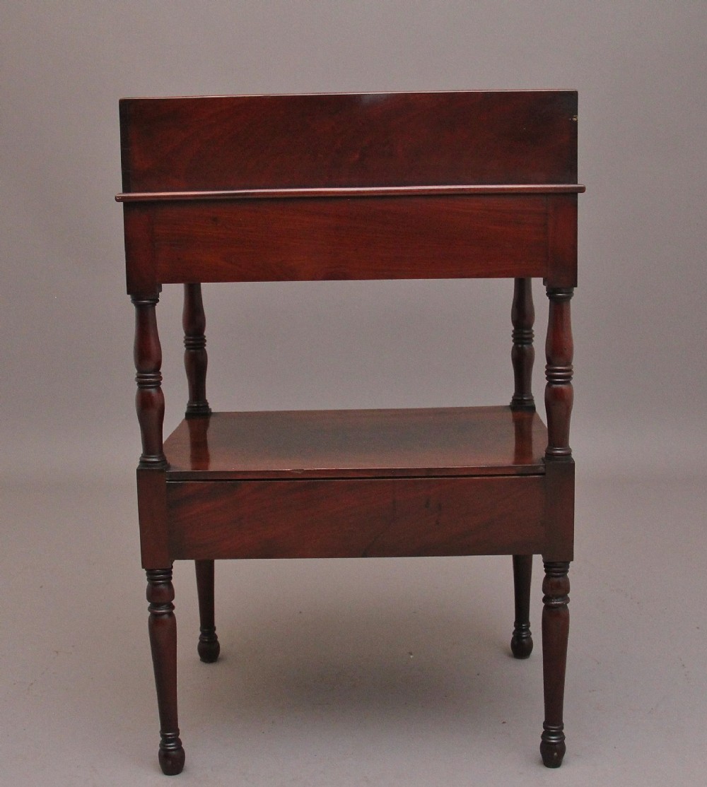 An early Victorian mahogany washstand featuring a gallery splashback top with circular aperture cutouts, a central open shelf, turned legs, and a bottom drawer with brass handles. View XIII