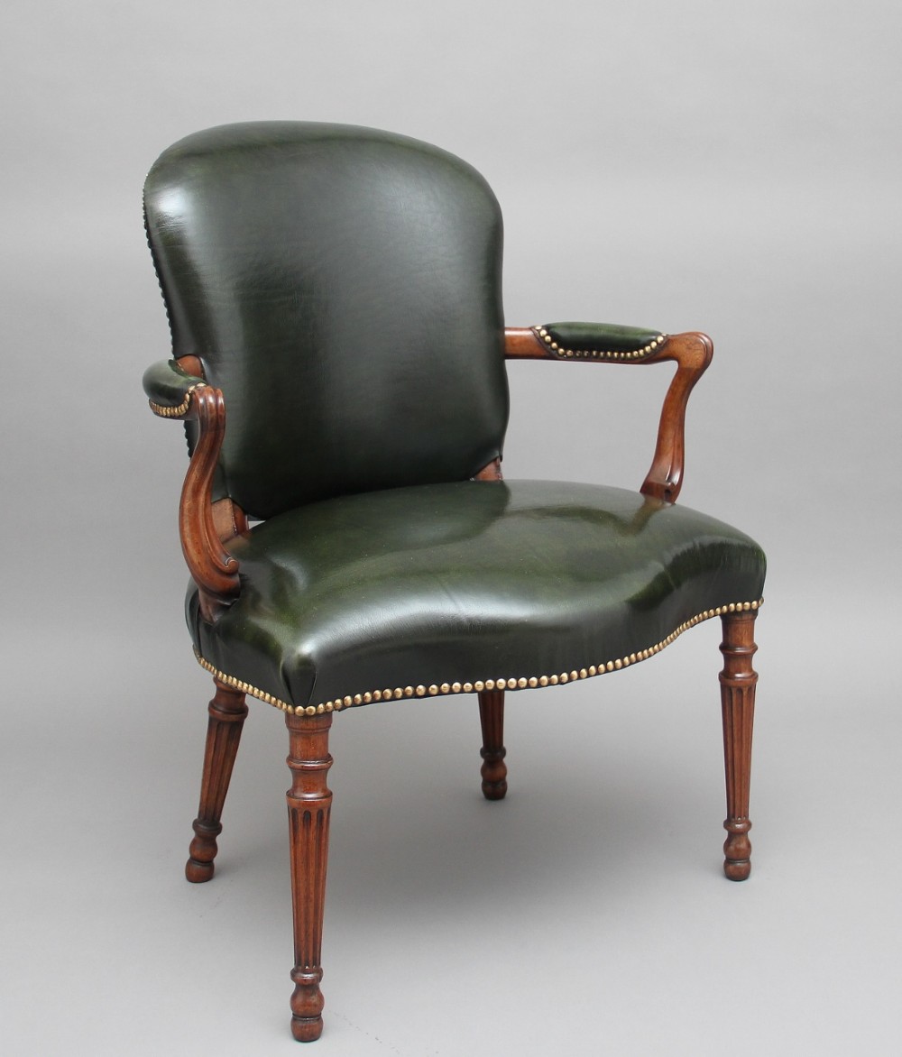 A 19th-century mahogany open armchair upholstered in dark green leather with brass studding and fluted front legs.