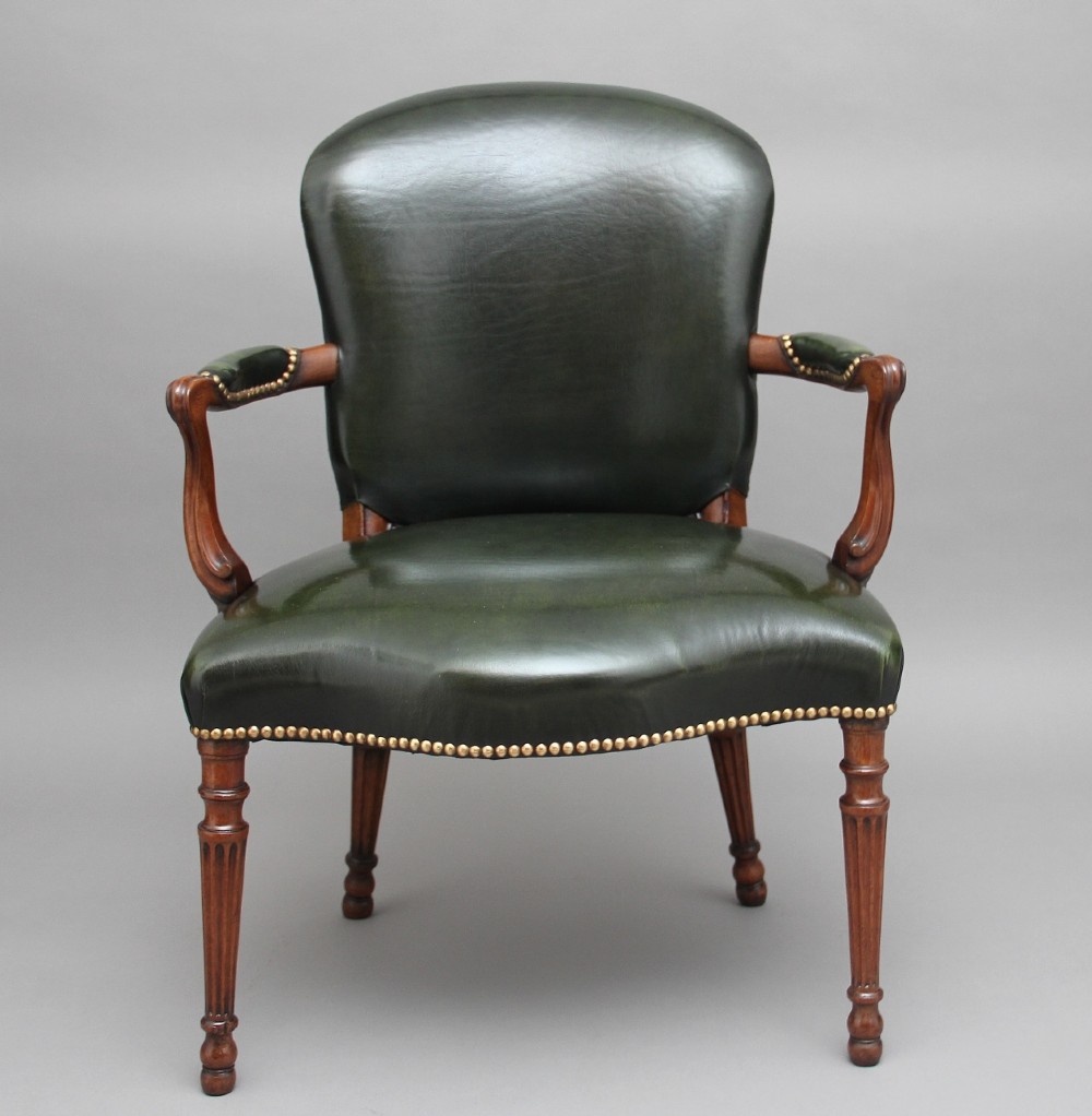 A 19th-century mahogany open armchair upholstered in dark green leather with brass studding and fluted front legs. View II