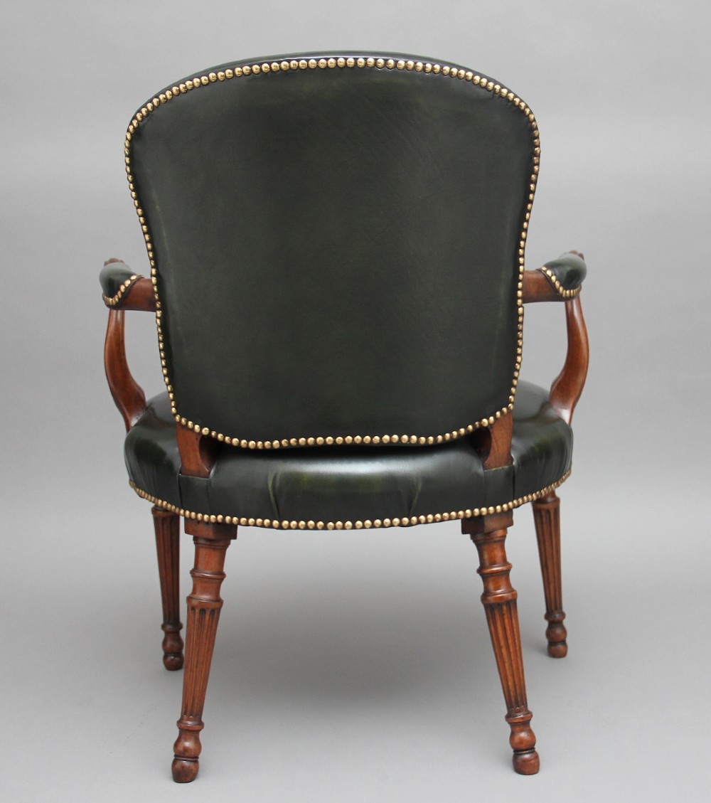 A 19th-century mahogany open armchair upholstered in dark green leather with brass studding and fluted front legs. View IV