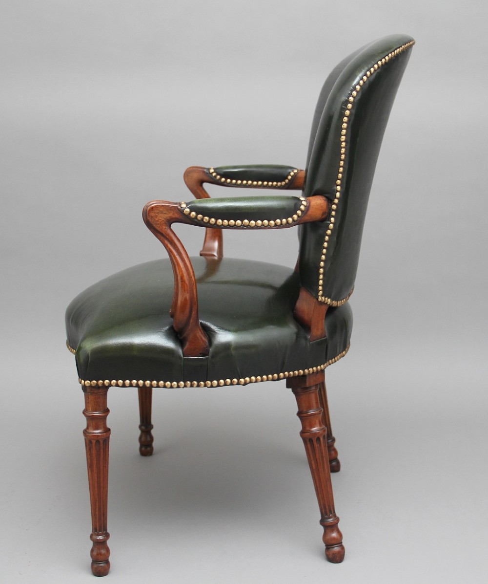 A 19th-century mahogany open armchair upholstered in dark green leather with brass studding and fluted front legs. View V
